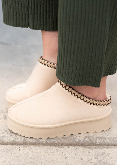 Side view of the beige suede clogs