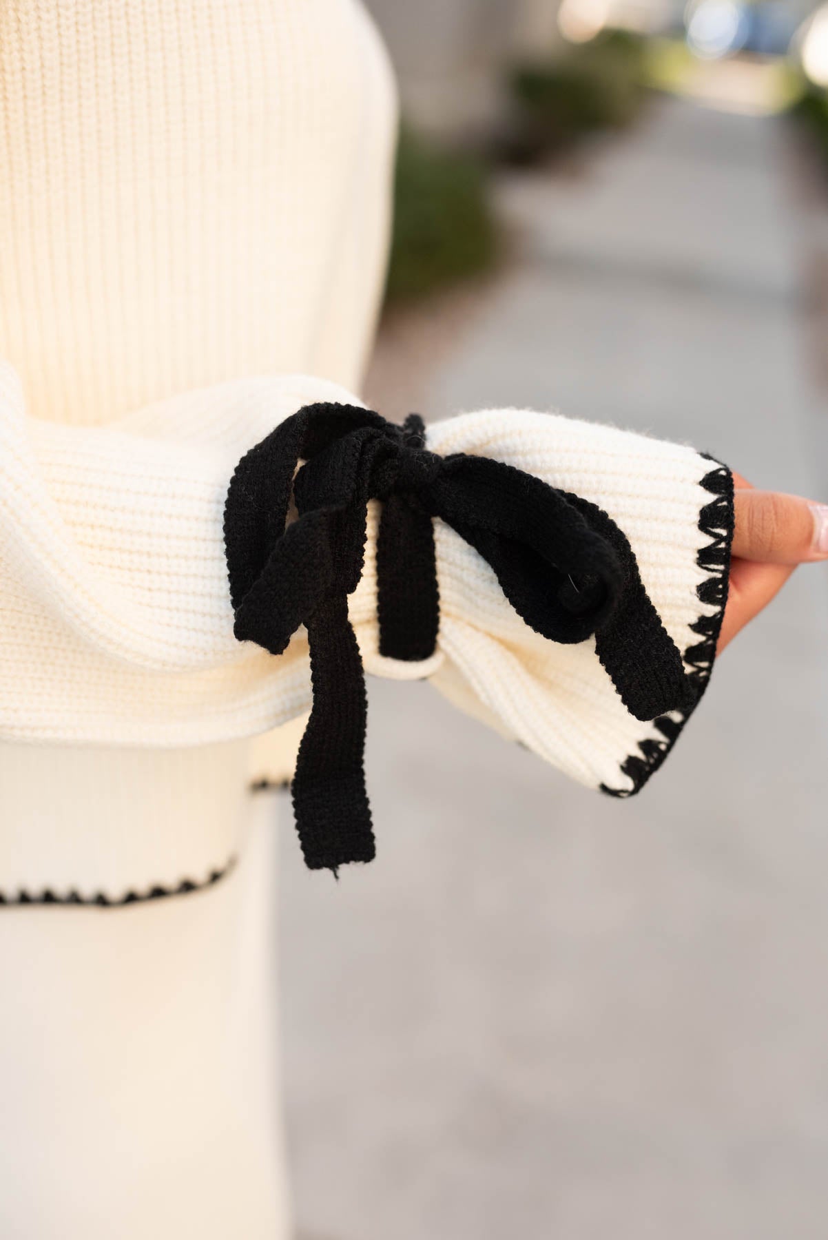 Sleeve on the cream knit sweater with black tie