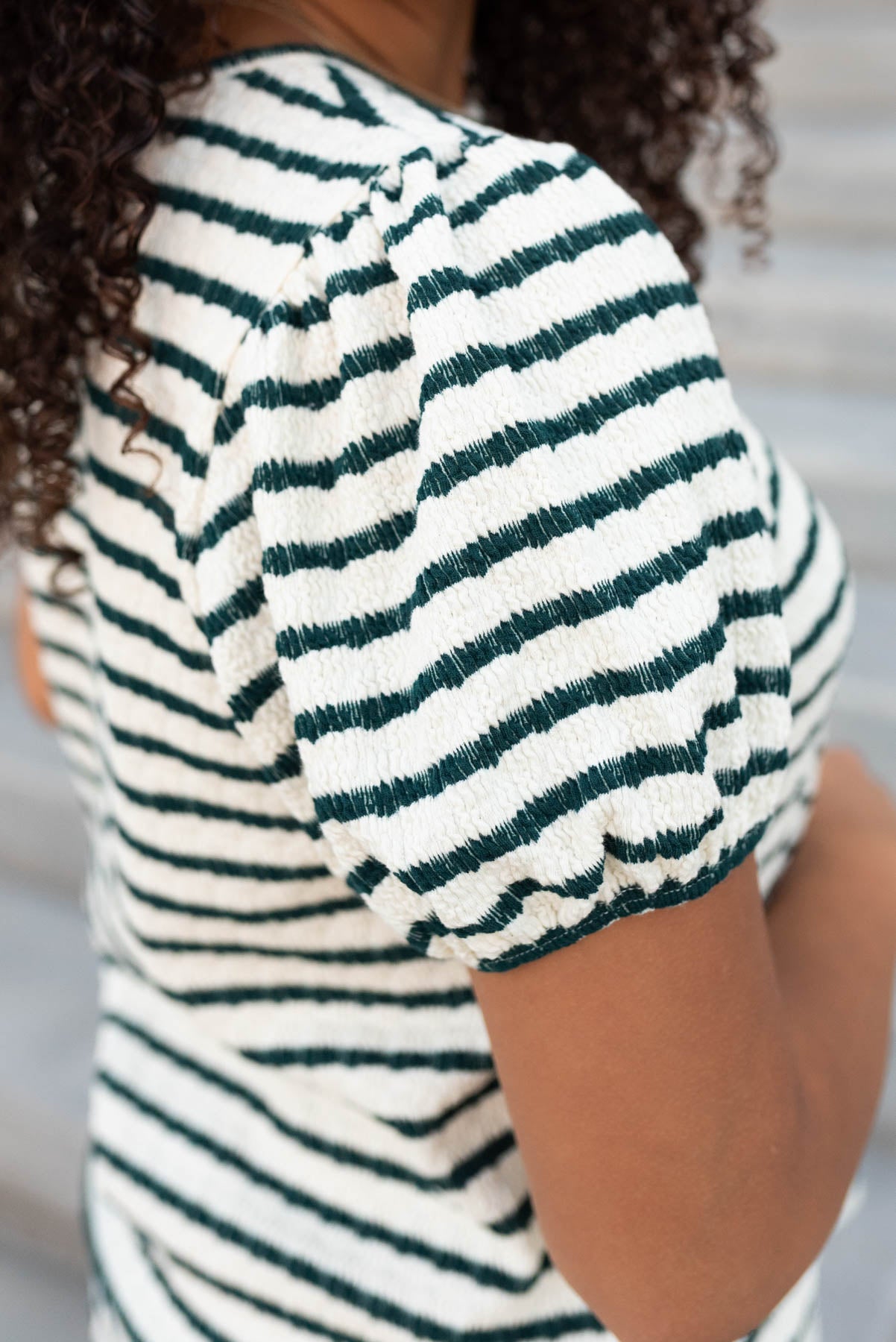 Close up of the sleeve and fabric of the emerald stripe textured top