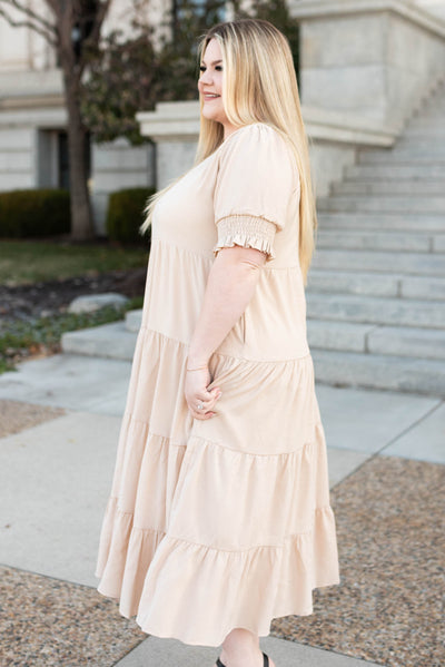 Side view of a plus size tiered cream dress