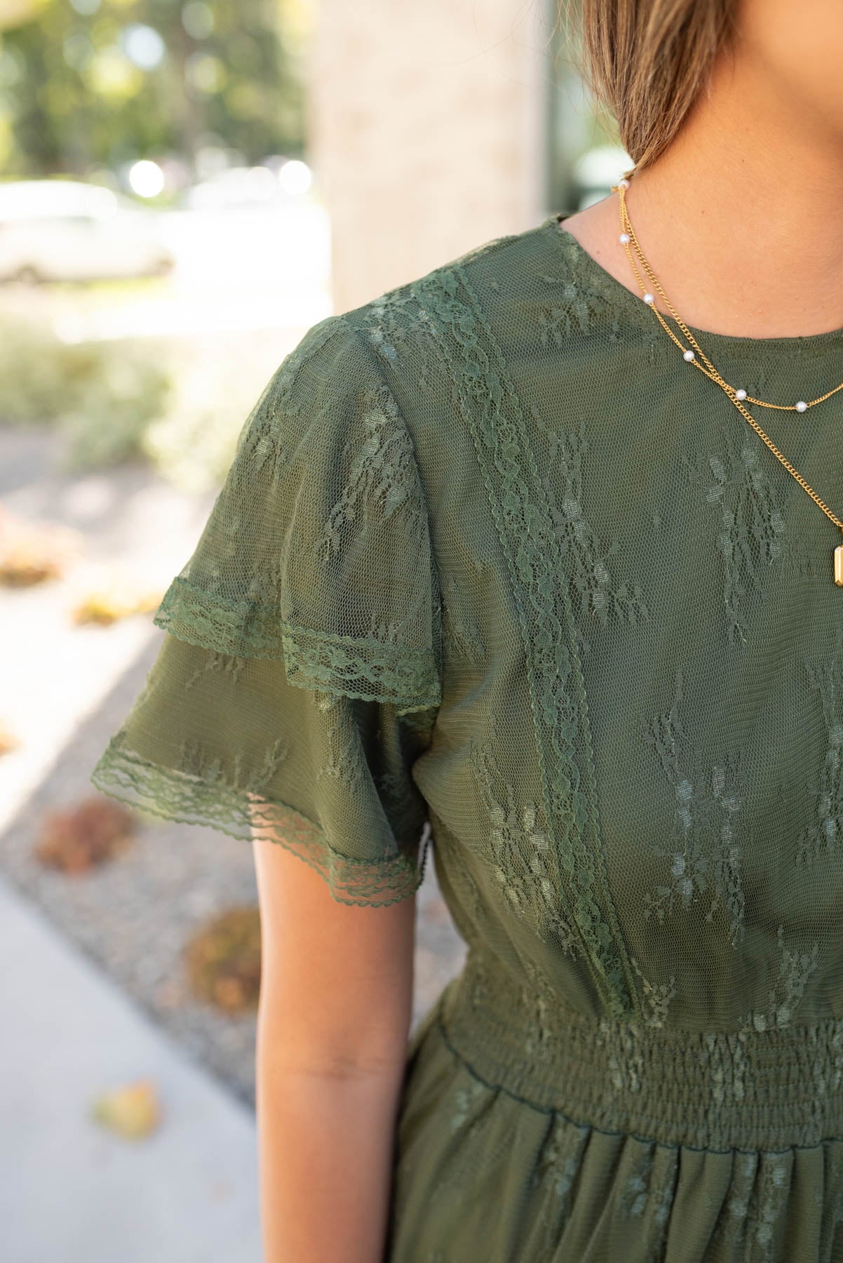 Close up of the sleeve and fabric on the dark green floral lace dress