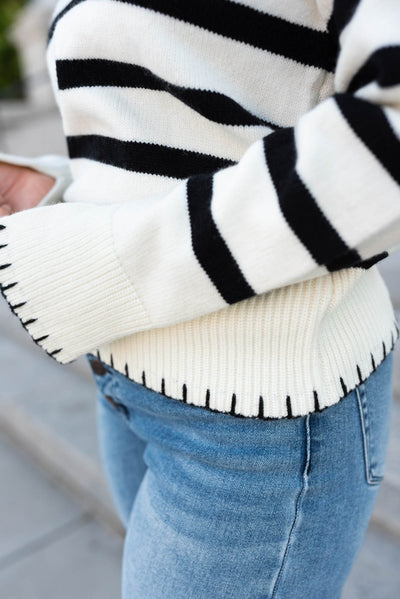 Close up of the stitching on the cuffs and waistband of the ivory black stripe sweater