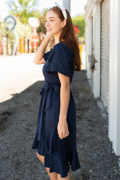 Side view of the navy ruffle tie dress