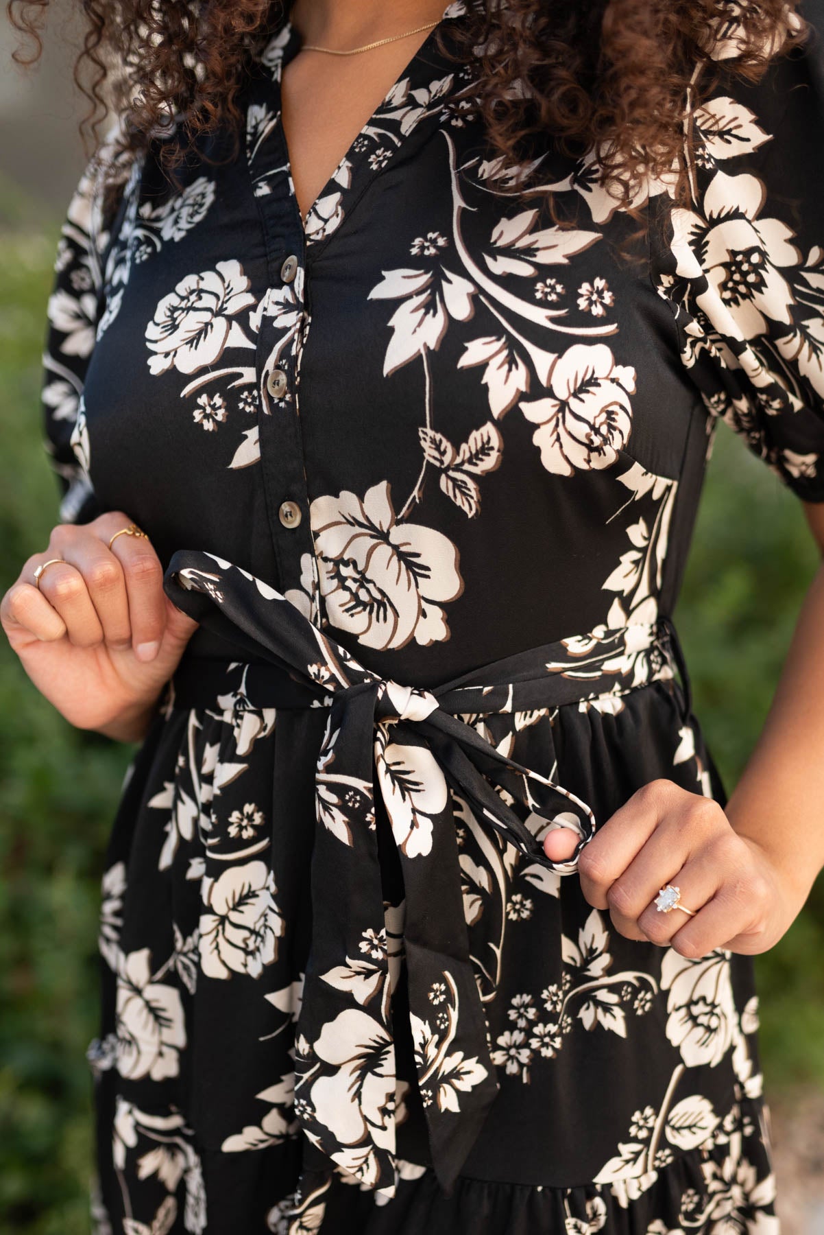 Close up of the fabric and the tie at the wasit on the black floral button tiered dress