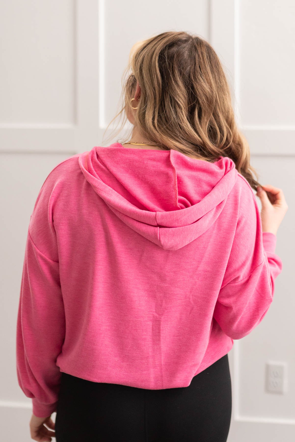 Back view of a hot pink half zip pullover with a hood