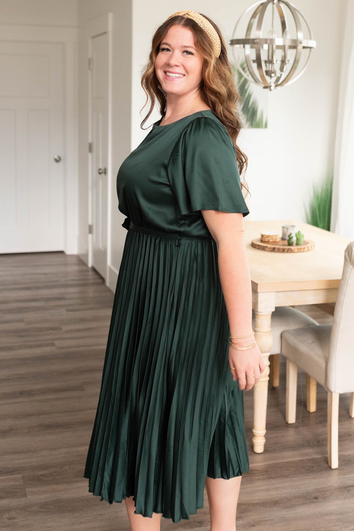 Side view of the hunter green satin pleat dress in plus size