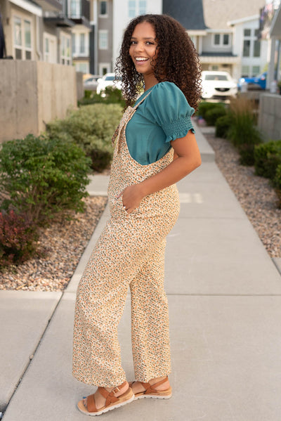 Side view of the cream floral corduroy overalls