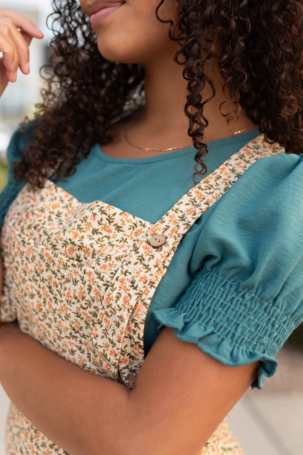 Close up of the button straps and fabric on the cream floral corduroy overalls