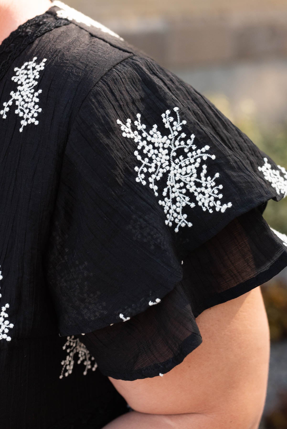 Close up of the sleeve and embroidery on the black embridered dress