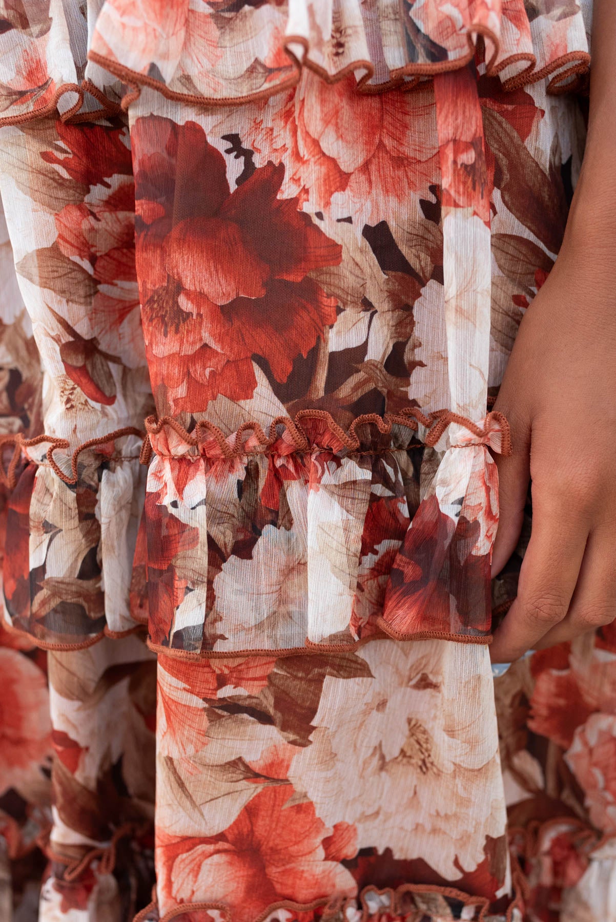 Close up of the fabric rust flroal ruffle dress