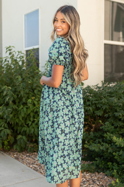 Side view of a short sleeve dark green dress with floral print