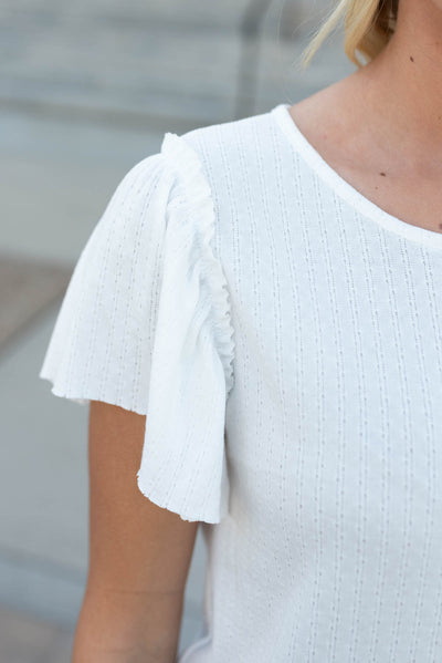 Close up on the ruffle sleeve on the off whtie textured top