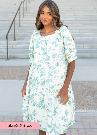 Front view of the green floral tiered dress with puff sleeves that have cuffs