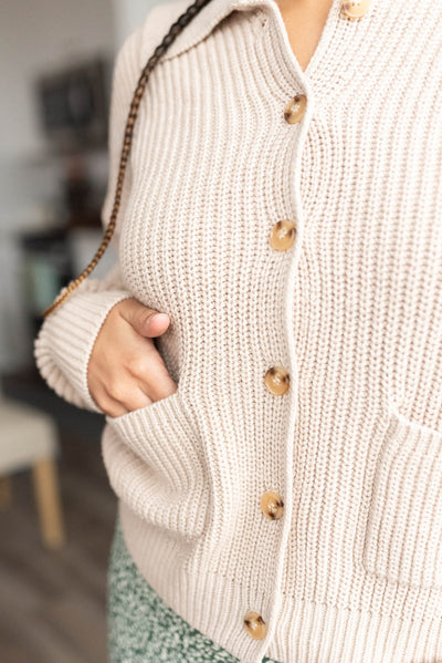 Close up of the buttons and pockets on the taupe collard button down cardigan