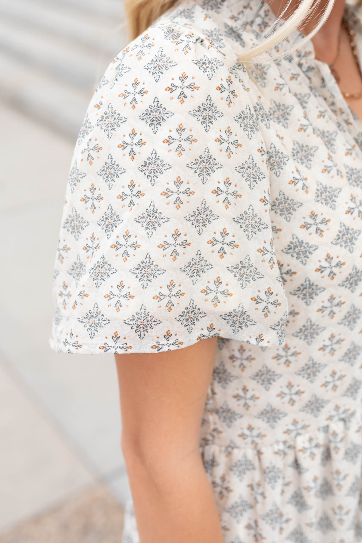 Close up of the sleeve and fabric on the cream pattern dress