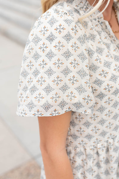 Close up of the sleeve and fabric on the cream pattern dress