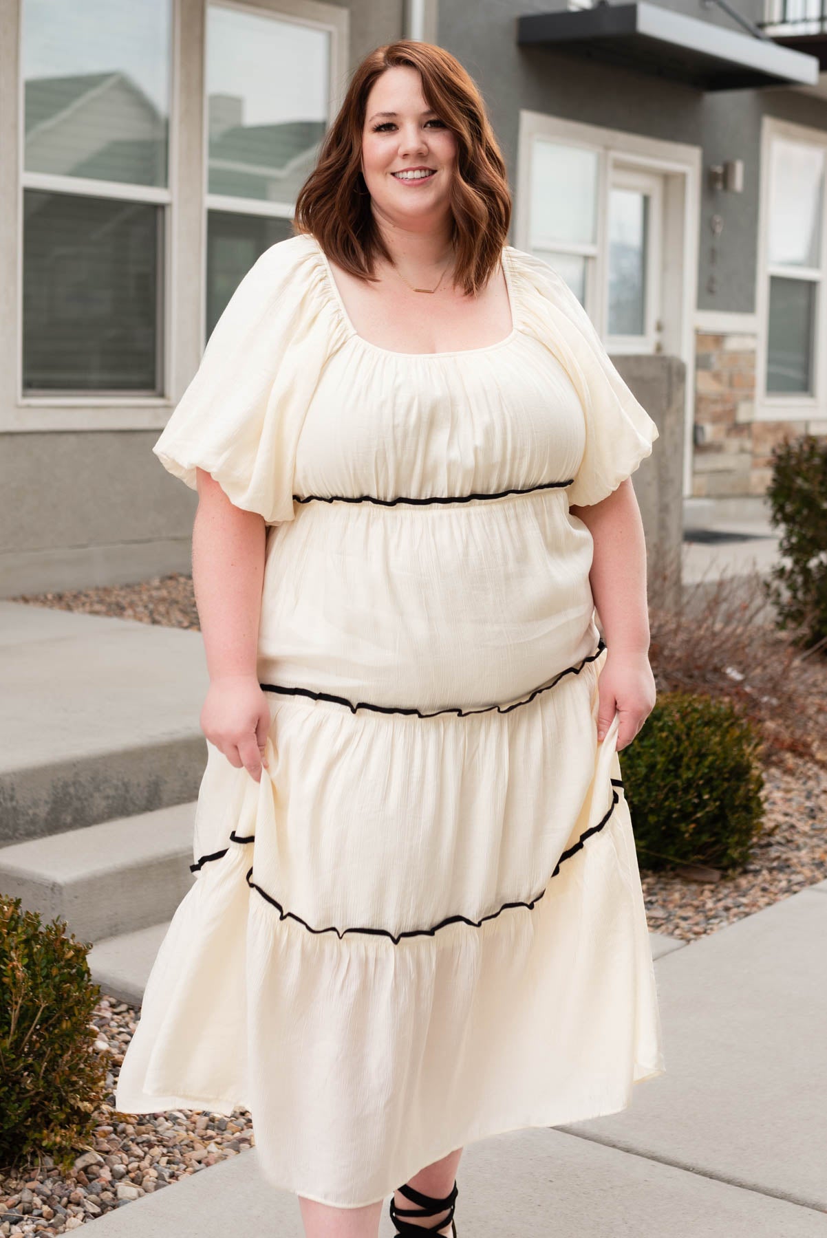 Plus size cream ruffle tiered dress with black trim.