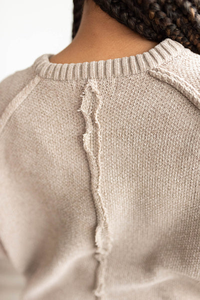 Back view of the taupe knitted sweater with raw seam