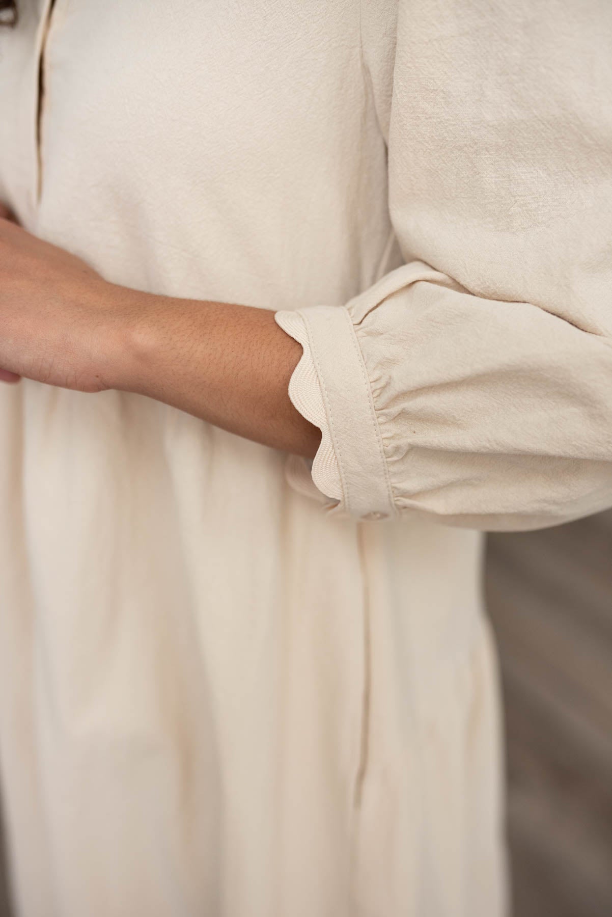 close up of the sleeve and cuff detail on the beige buttond own dress