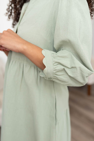 Close up of the sleeve and trim on the sage button down dress