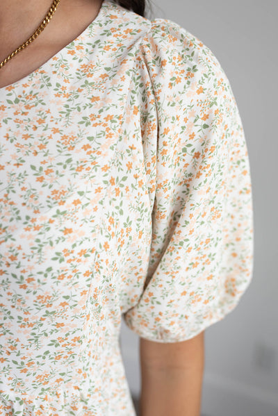 Close up of the fabrc pattern and sleeve on the orange floral dress