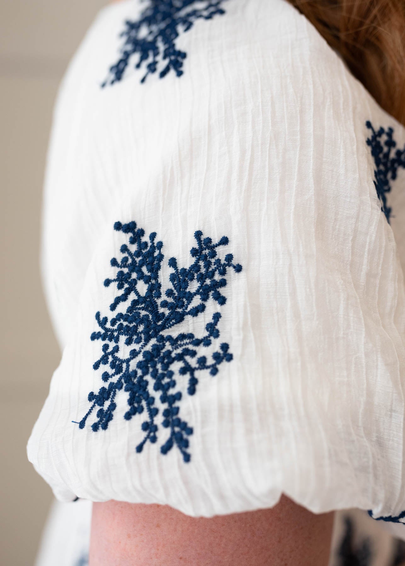 Close up of the navy embroidery on the ivory embroidered dress