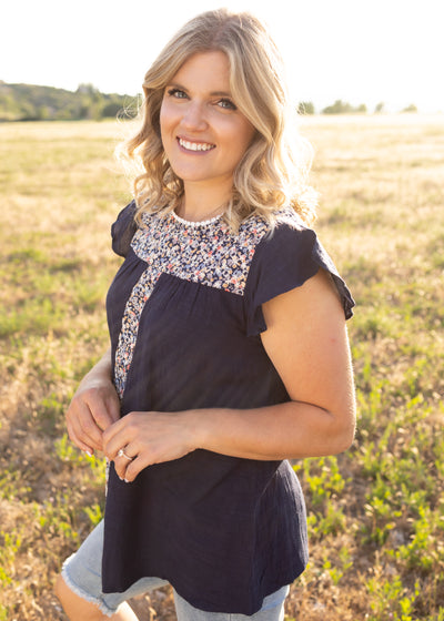 Side view of a navy top with floral print at neck