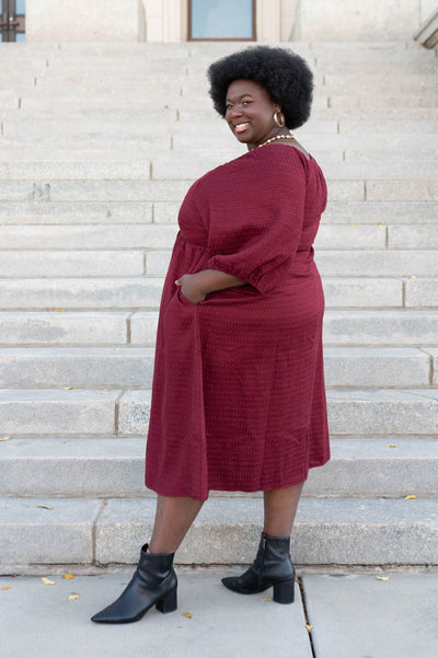 Side view of the burgundy textured dress in plus size with pockets