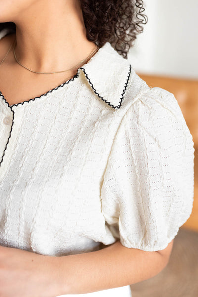 Close up of the black stitching on the collar and neckline of the cream collared top