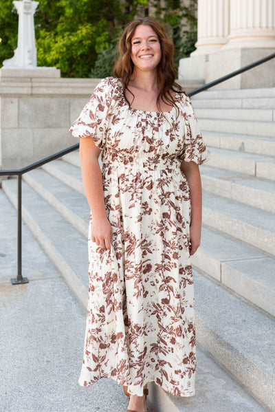 Front view of the mocha floral tiered dress with pockets and puff sleeves